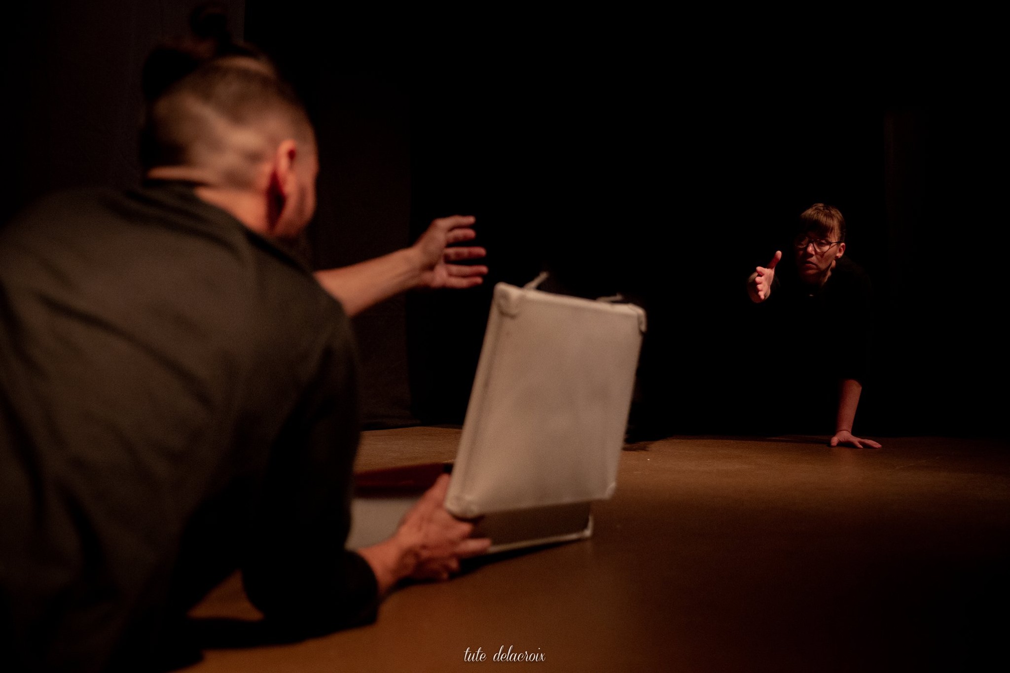 Dos personas sobre el piso, estirando sus manos de uno y otro lado, intentando agarrarse.