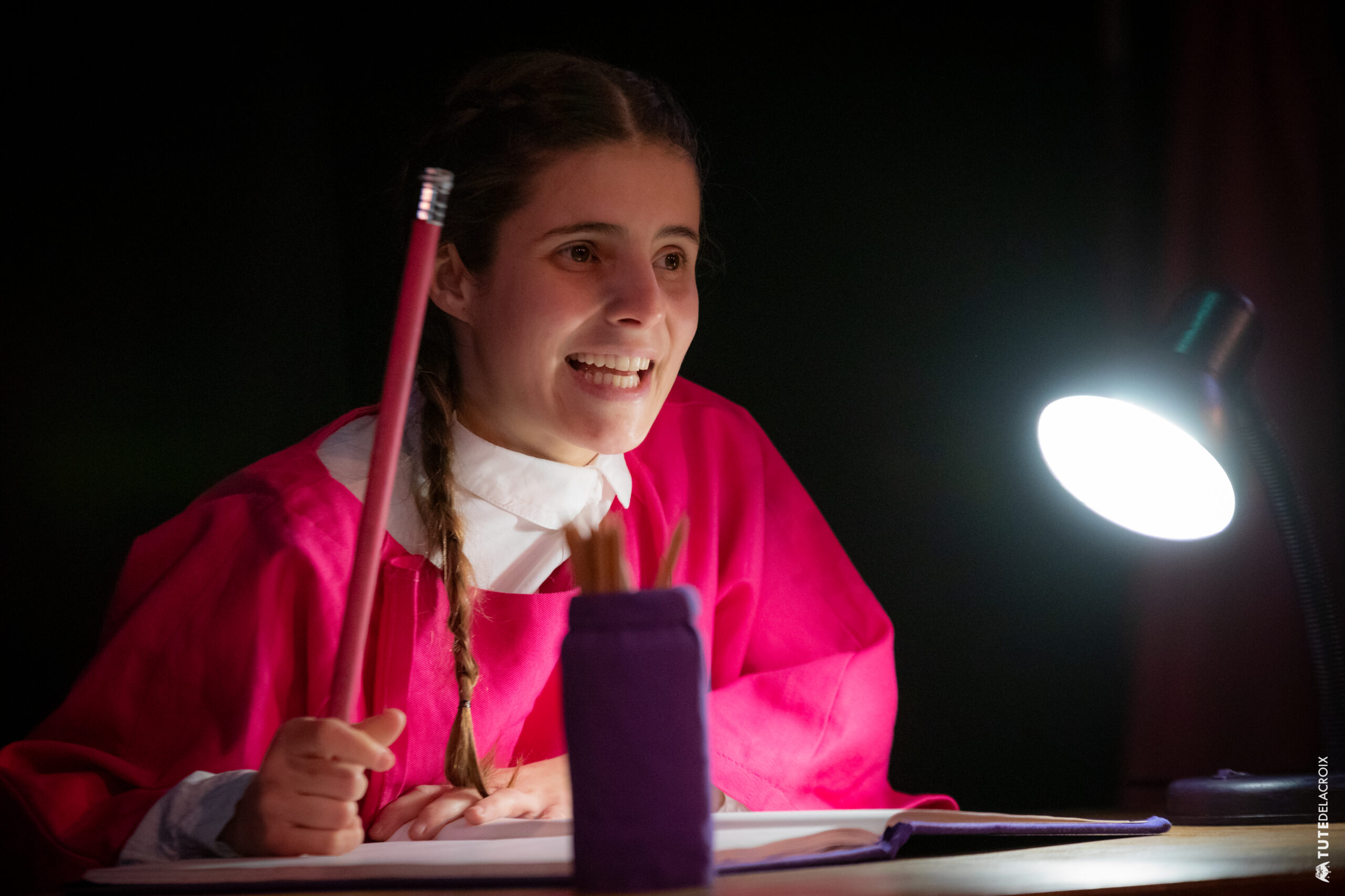 Una chica con lápiz en mano y a pura sonrisa en sus pensamientos, a punto de escribir