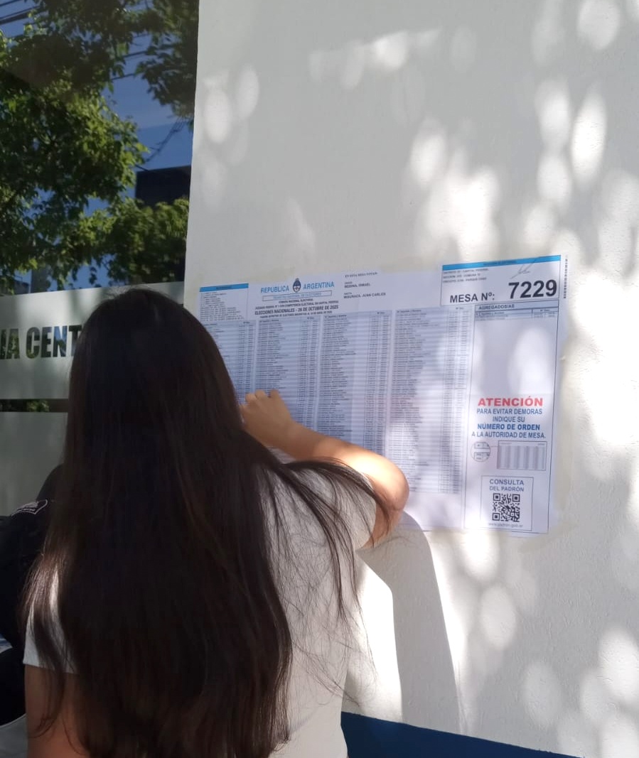 una joven buscando su nombre en la lista para votar