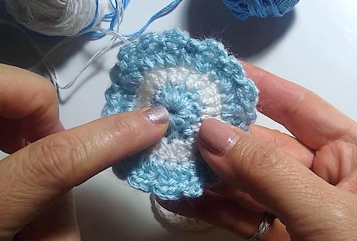 Dos manos tejiendo una escarapela con lana